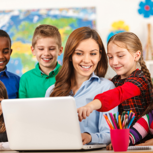 teacher with young students looking at laptop